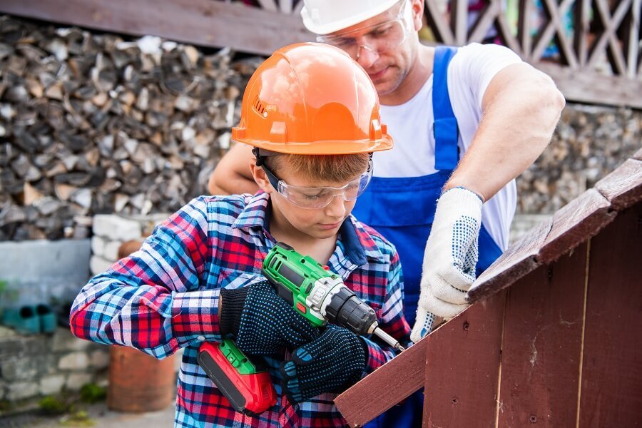 father teaching his son how to build a doghouse