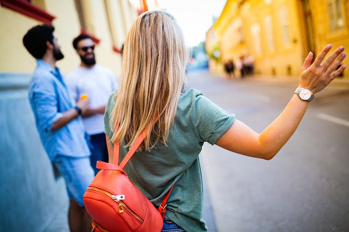 A woman travelling and waiting for a taxi car on the street